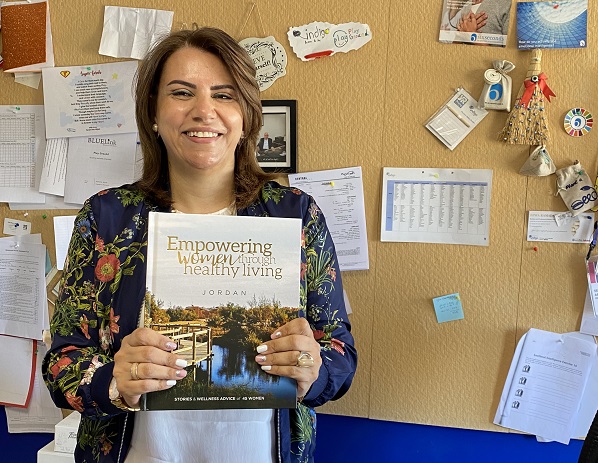 woman smiling and holding the Empowering Women through Healthy Living book