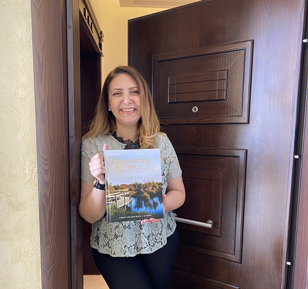 woman smiling and holding the Empowering Women through Healthy Living book