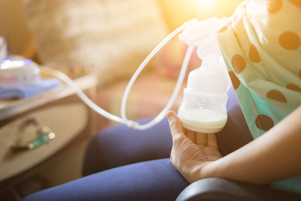 A Mom Bumping milk out of her breast in a bottle for her kid