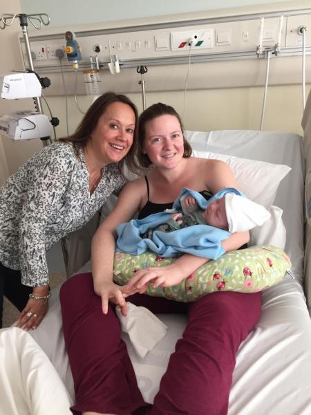a picture of a women and her baby boy with the doula in the hospital after giving birth