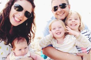 a family of 5 smiling to the camera